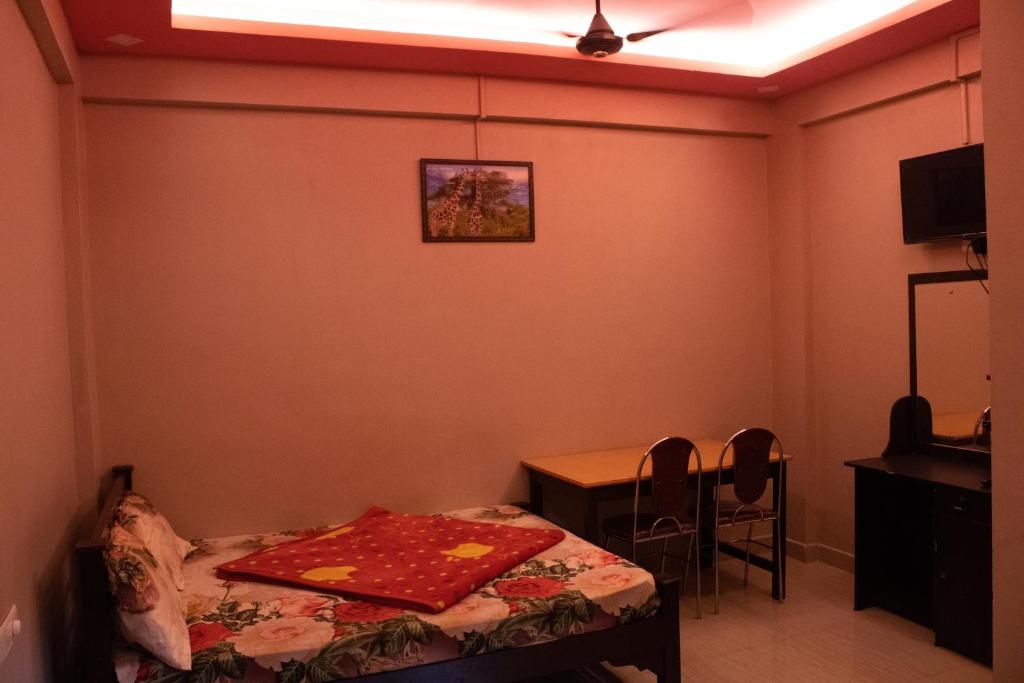 a room with a bed and a table and a ceiling fan at Mountainmist Residency in Ramakkalmedu