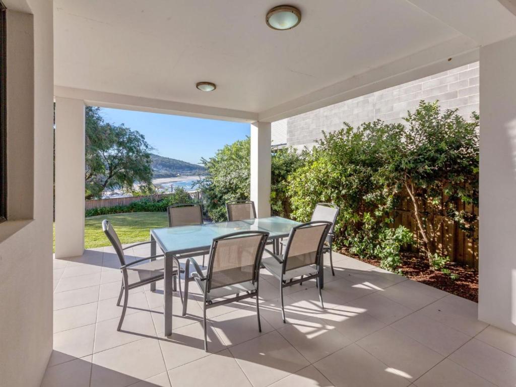 een eetkamer met een tafel en stoelen op een patio bij Beach House 1 20 Pacific Drive in Fingal Bay