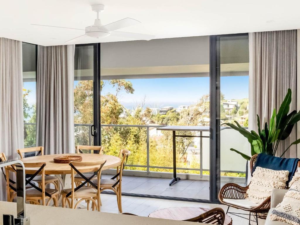 een woonkamer met een tafel en stoelen en een groot raam bij Sea to Believe in Gerringong