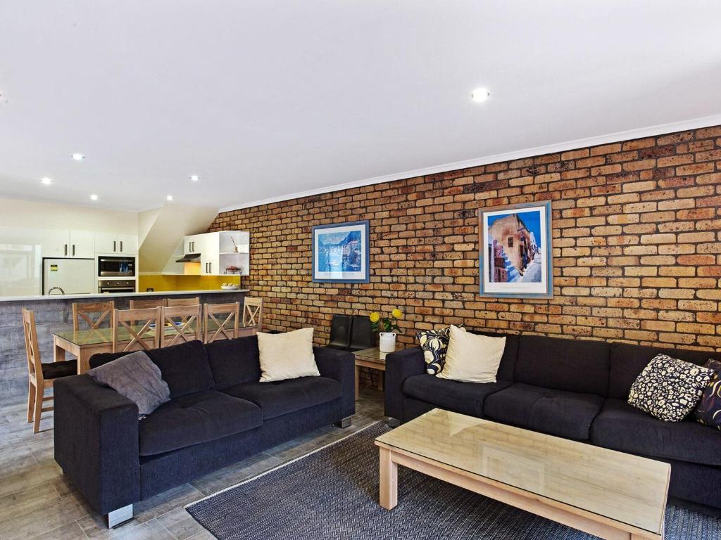 a living room with two couches and a brick wall at Kurrawa Close 2 14 in Nelson Bay