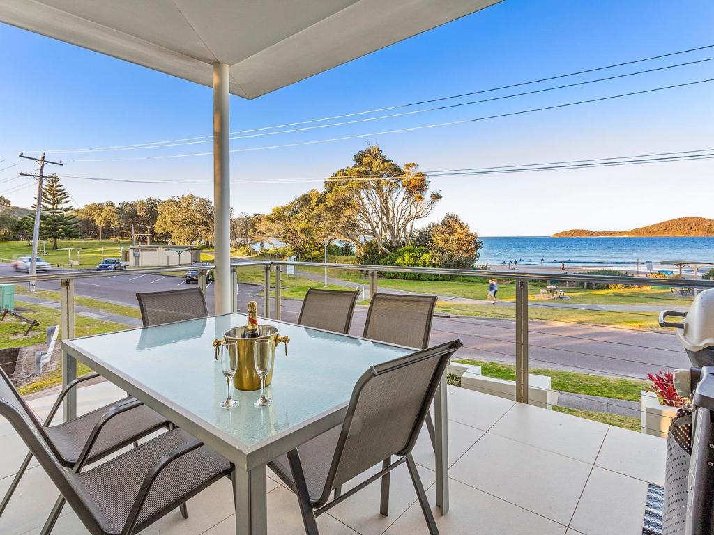 einen Tisch und Stühle auf einer Veranda mit Meerblick in der Unterkunft serenity at Fingal Bay 1 in Fingal Bay