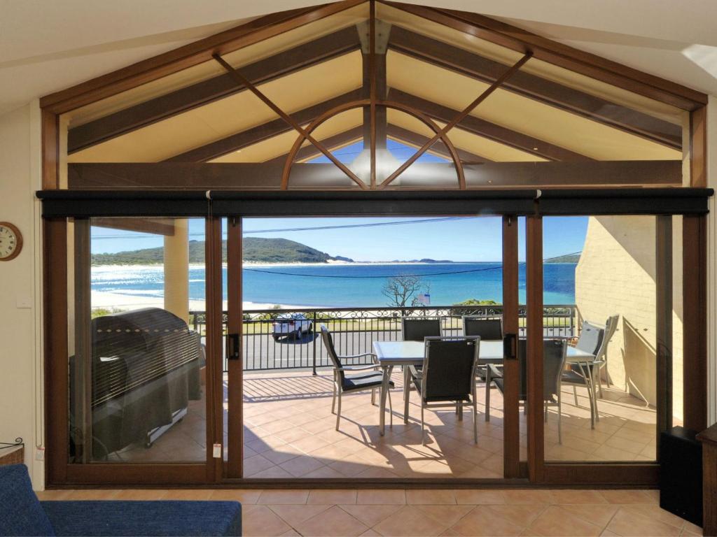 Zimmer mit einem Balkon mit Tisch und Stühlen in der Unterkunft Marine Dr 2 70 Fingal Bay in Fingal Bay