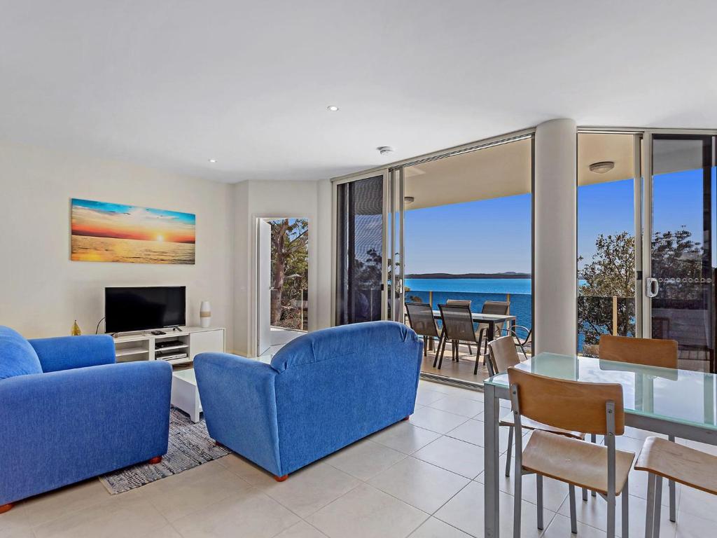 a living room with blue furniture and a view of the ocean at Mirage 1 24 Gloucester Street in Nelson Bay