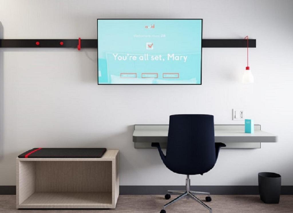 an office with a desk and a chair and a screen at avid hotels - Zeeland by IHG in Holland