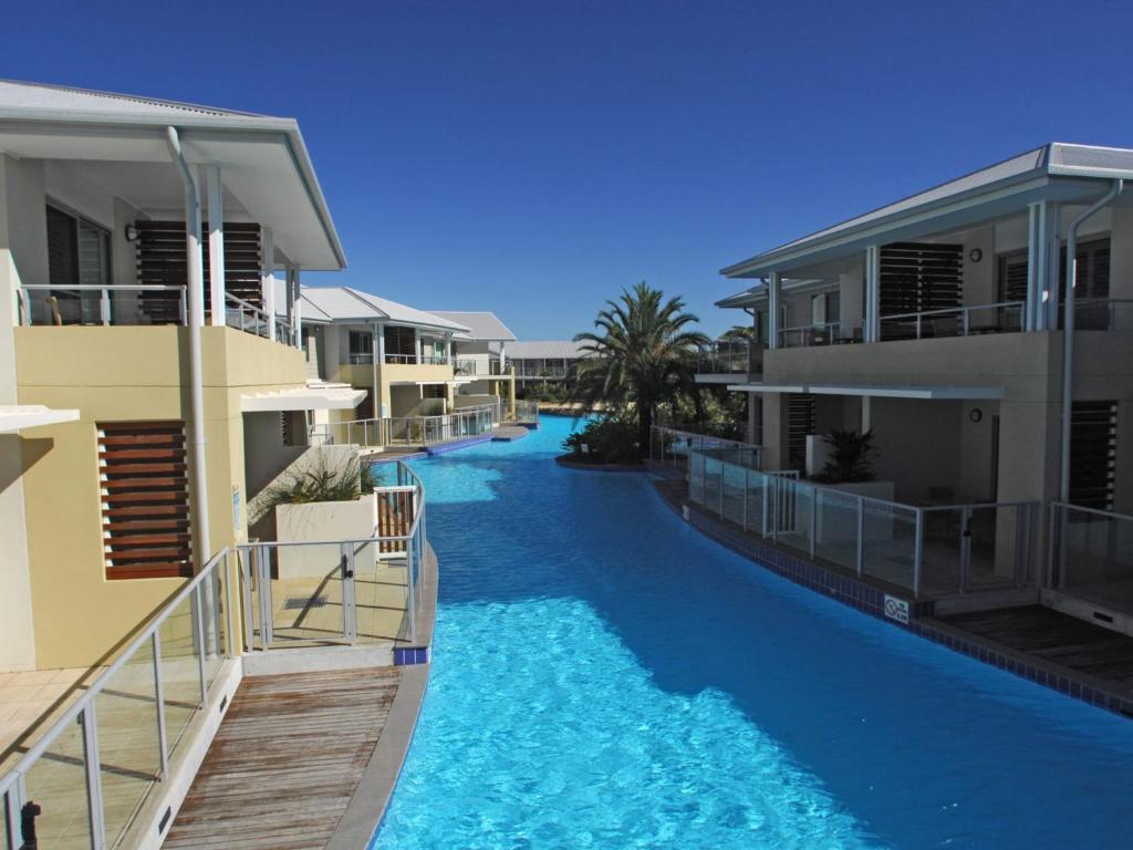 a resort pool with blue water between two buildings at Pacific Blue Apartment 139, 265 Sandy Point Road in Salamander Bay