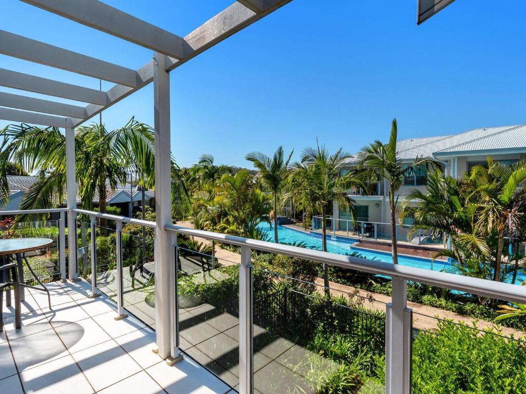 a balcony with a view of the pool and palm trees at Pacific Blue Townhouse, 351/265 Sandy Point Road in Salamander Bay