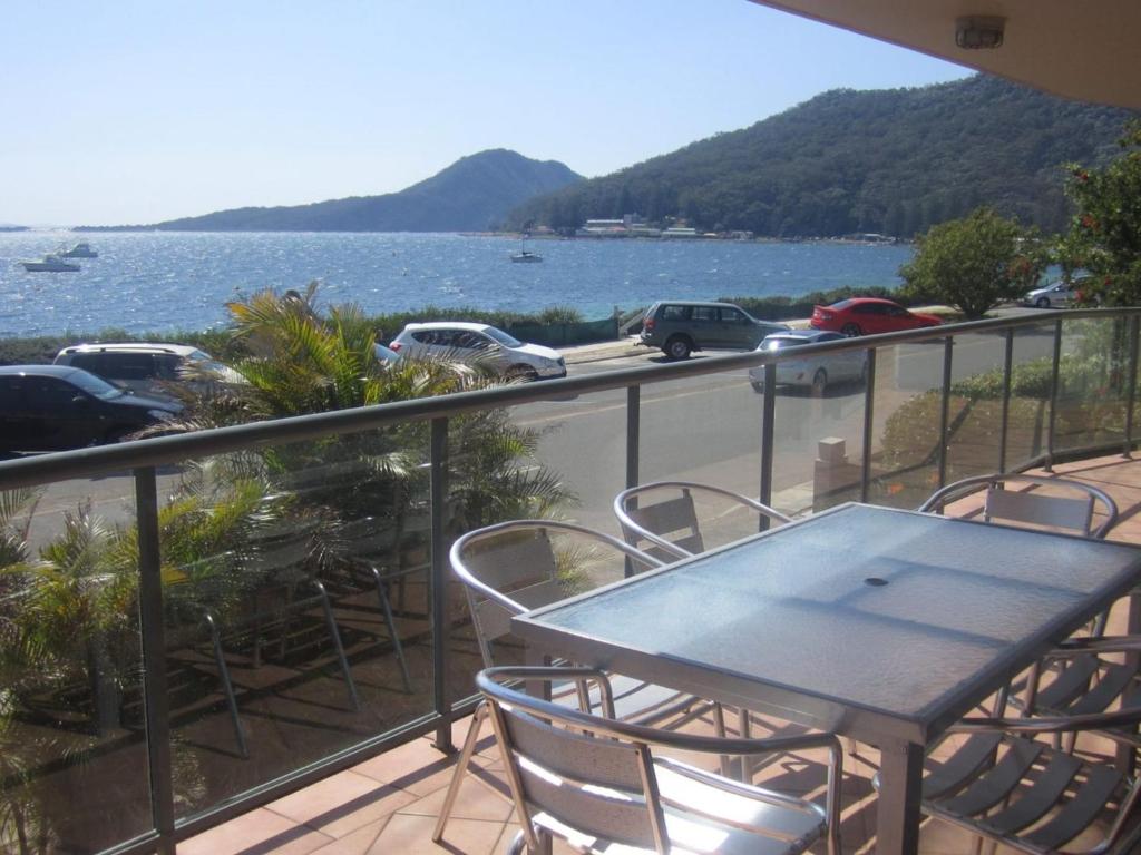 a table and chairs on a balcony with a view of the water at Palm Beach 33B Shoal Bay Road in Shoal Bay