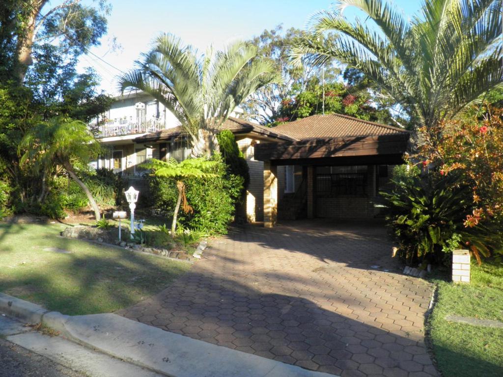 une maison avec des palmiers et une allée dans l'établissement Pelicans Perch 8 Verona Road, à Shoal Bay