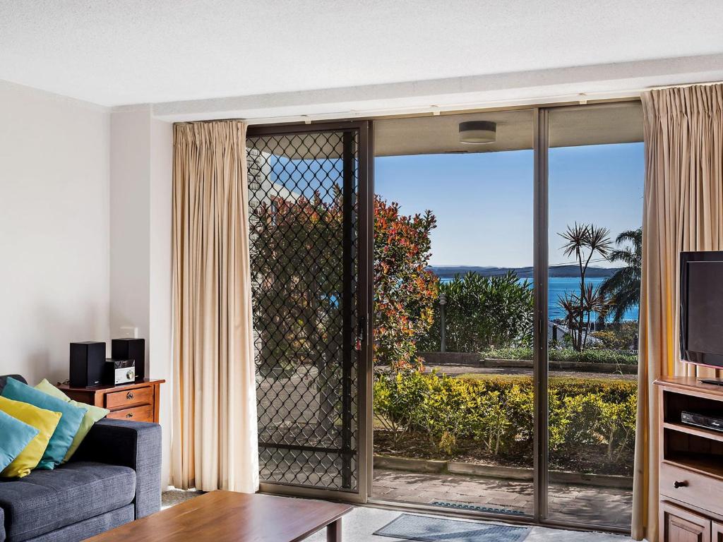 a living room with a sliding glass door with a view of the ocean at Portside Unit 8 1 Donald Street in Nelson Bay