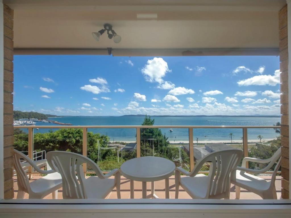a balcony with a table and chairs and a view of the ocean at Quarterdeck Unit 3 12 Magnus Street in Nelson Bay