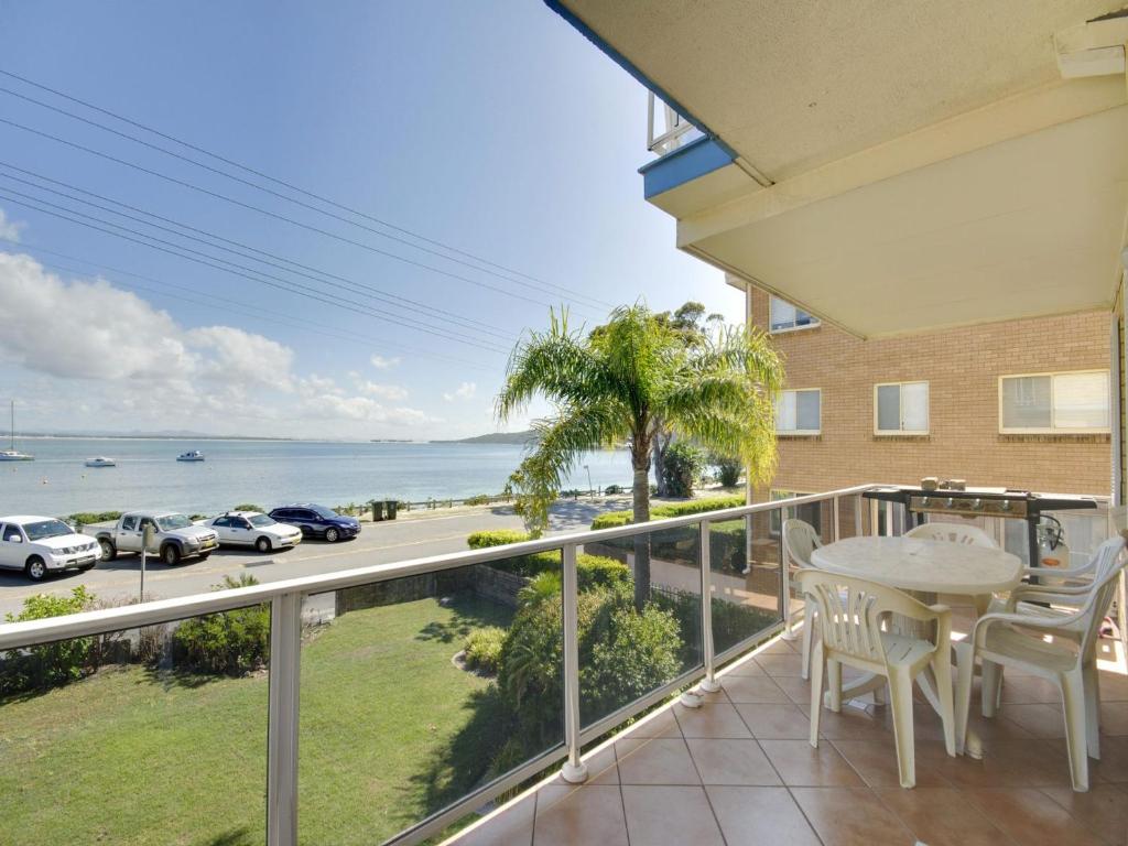 balcón con mesa, sillas y vistas al océano en Castaways Unit 4 17 Shoal Bay Road, en Shoal Bay