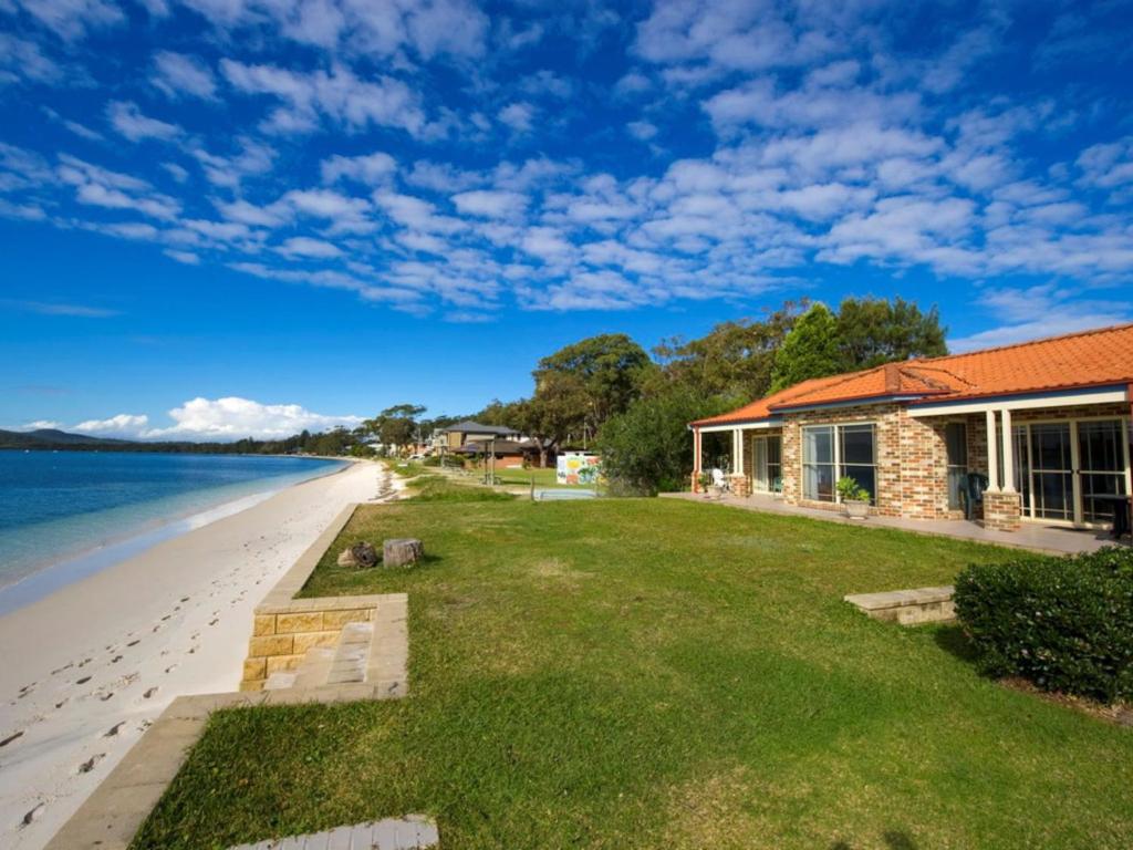 a house on the beach next to the ocean at Cook Street 4 in Salamander Bay