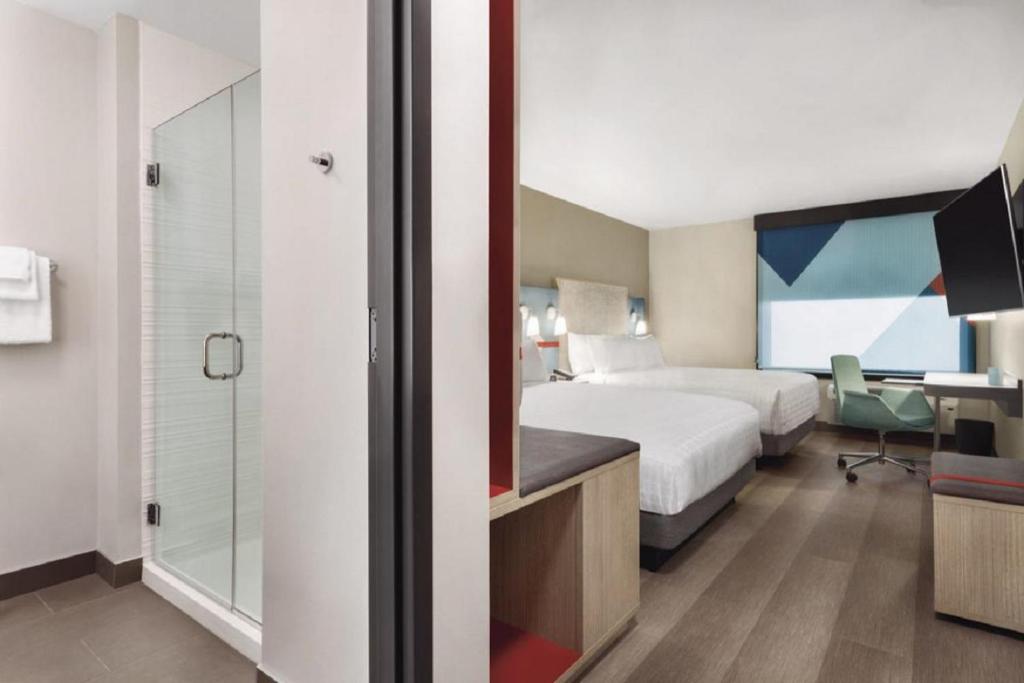 a hotel room with a bed and a glass shower at avid hotels - Zeeland by IHG in Holland