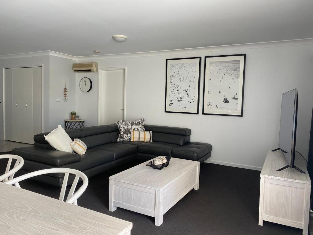 a living room with a black couch and a table at Seashells Apartment 9, 21-23 Magnus Street in Nelson Bay