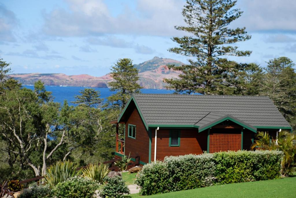 a house with a view of the water and mountains at Coast Norfolk Island in Burnt Pine