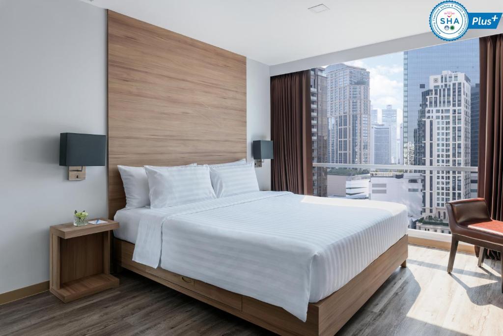 a bedroom with a large white bed and a large window at Adelphi Grande Sukhumvit in Bangkok