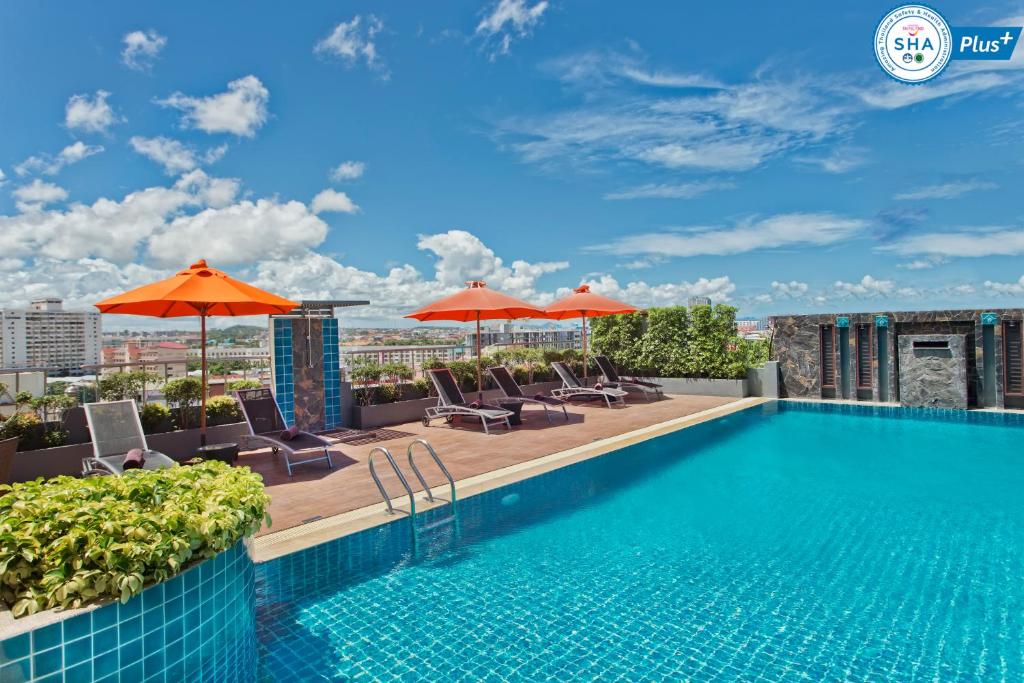 芭達雅中心的住宿－Adelphi Pattaya - SHA Extra Plus，一座带遮阳伞的建筑屋顶上的游泳池