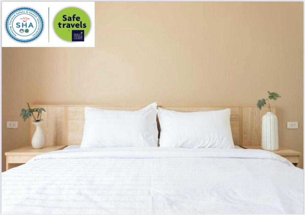 um quarto com uma cama branca com lençóis e almofadas brancos em O2 Hotel Lopburi em Lopburi