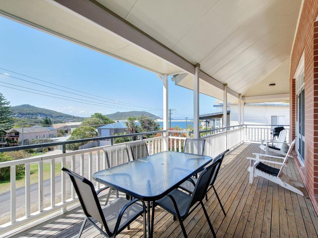 a patio with a table and chairs on a balcony at Surf Break Unit 10B Tuna Cresent Upstairs in Fingal Bay