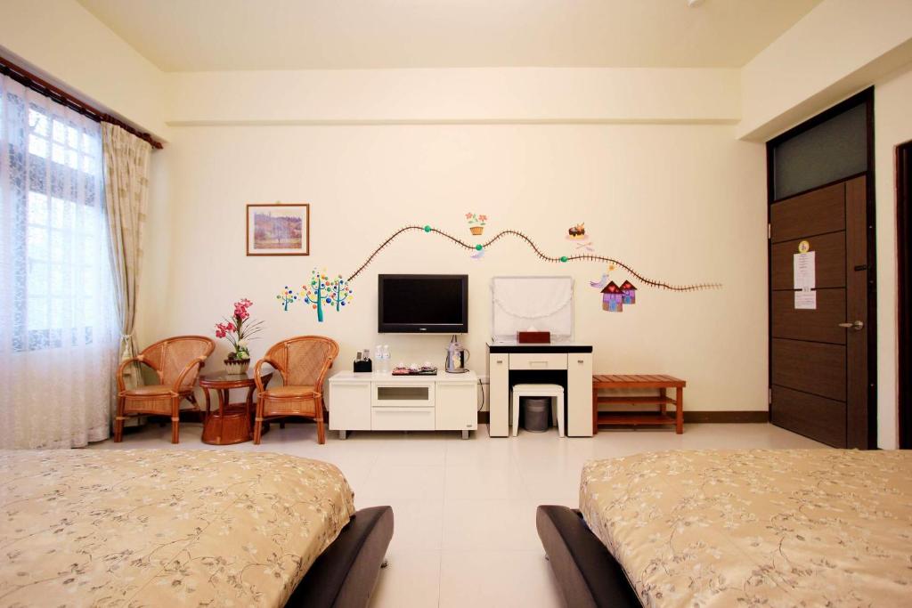 a bedroom with two beds and a tv on the wall at Green Window Homestay in Hualien City