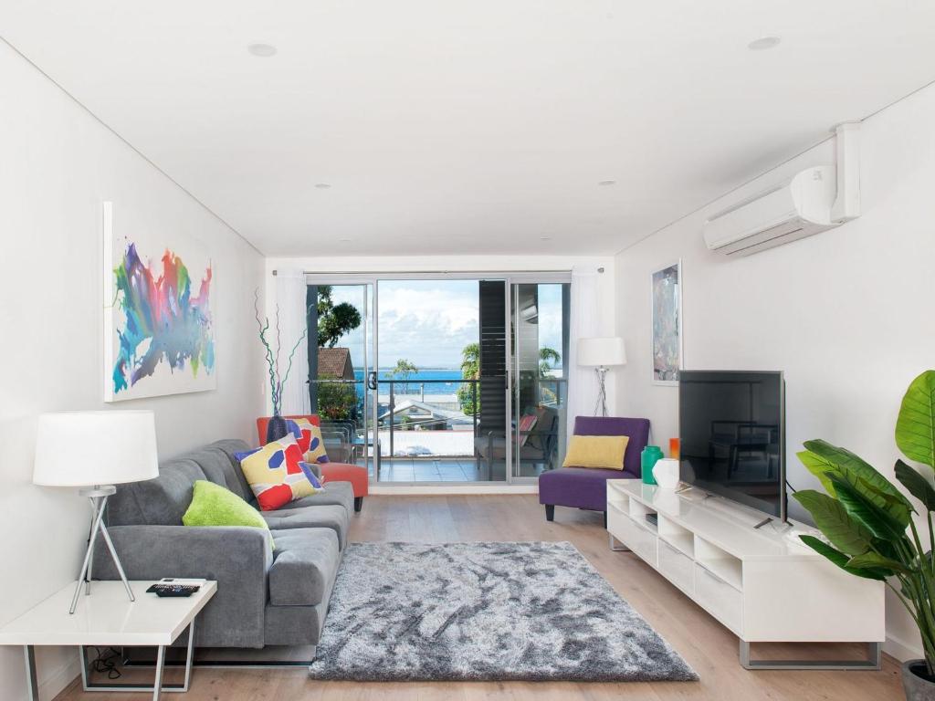 een woonkamer met een bank en een tv bij The Shoal Apartments, Unit 201/4-8 Bullecourt Street in Shoal Bay