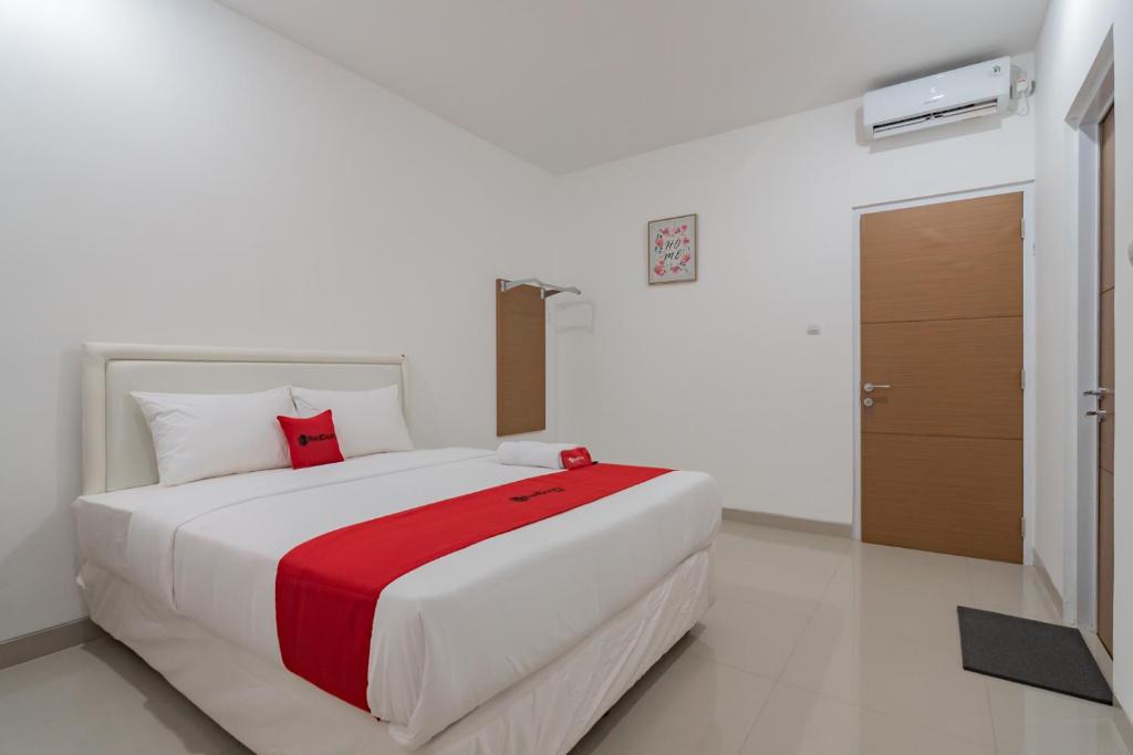 een slaapkamer met een groot wit bed en een rode deken bij Hotel Sukahaji Street Bandung Redpartner in Bandung