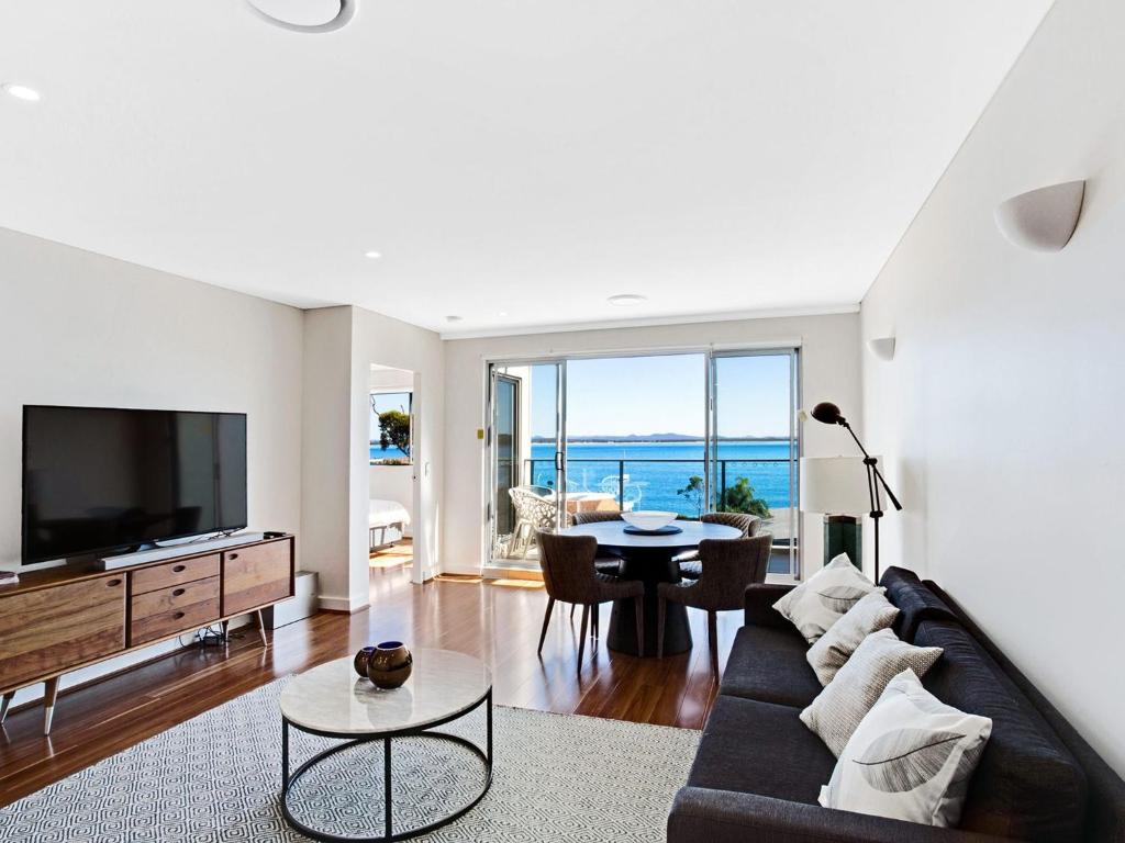 a living room with a couch and a tv and a table at The Shoal, Unit 510/4-8 Bullecourt Street in Shoal Bay