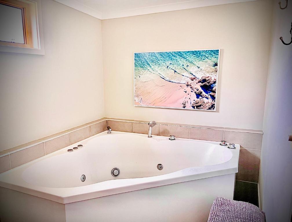La salle de bains est pourvue d'une baignoire et d'une peinture murale. dans l'établissement Churchill's B&B twin spa getaway Studio, à Swansea