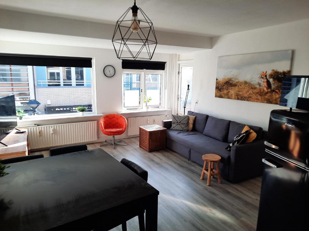 een woonkamer met een blauwe bank en een rode stoel bij Apartment Duinvos 150m from the beach in Noordwijk aan Zee