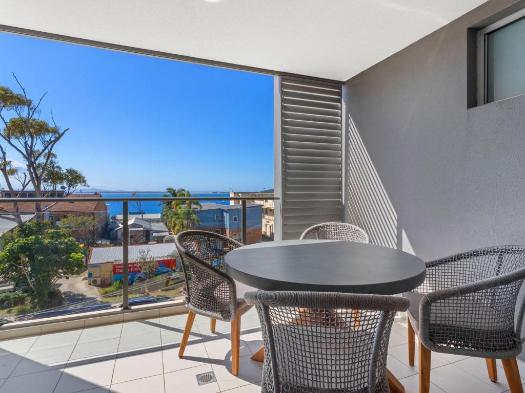 einen Balkon mit einem Tisch und Stühlen sowie Meerblick in der Unterkunft The Shoal Apartments Unit 306 6 Bullecourt in Shoal Bay