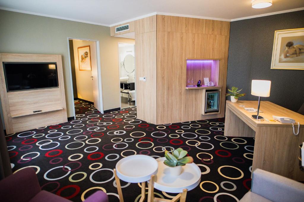 Garden Hotel Wellness és Konferencia في سزولنوك: غرفة في الفندق مع غرفة معيشة مع غرفة في الفندق