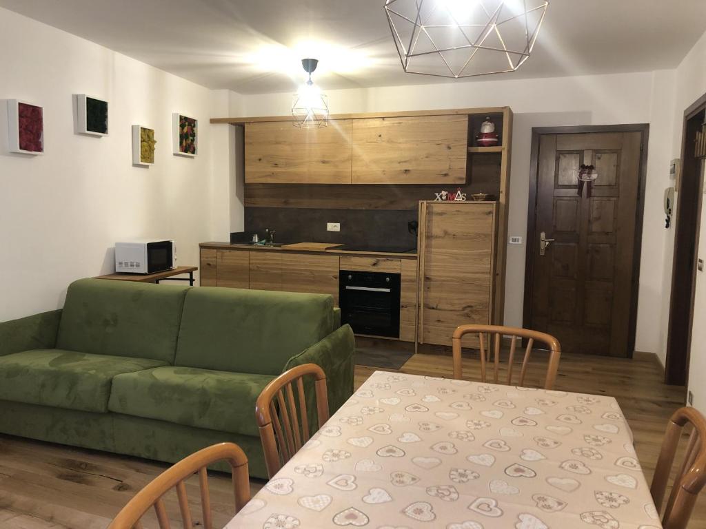 een woonkamer met een groene bank en een tafel bij 017 Trilocale, Pinzolo in Pinzolo