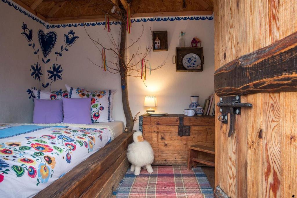 a bedroom with a bed with a white dog standing next to it at Folklórna chyža in Bojnice