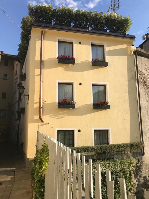 un bâtiment jaune avec des boîtes de fleurs sur lui dans l'établissement Maison du Passage, à Aoste