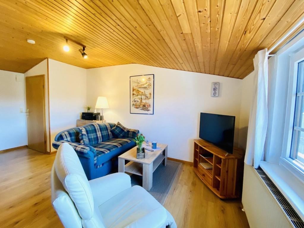 a living room with a blue couch and a tv at Trautes Heim Ferienwohnung Sued in Maasholm