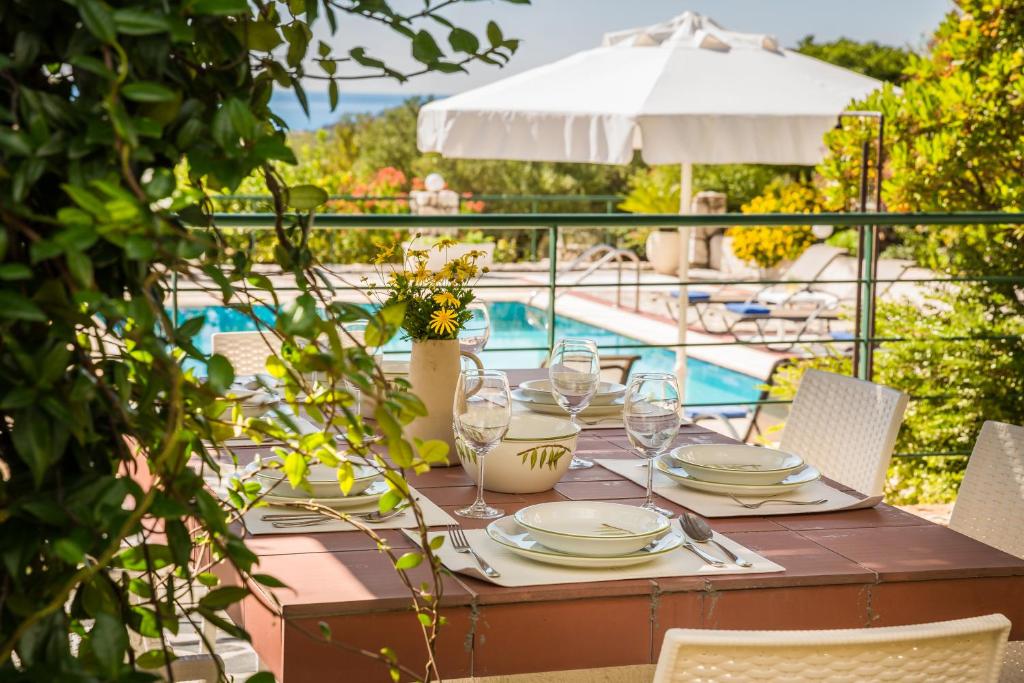 a table with plates and wine glasses next to a pool at Villa Petri in Trapezaki