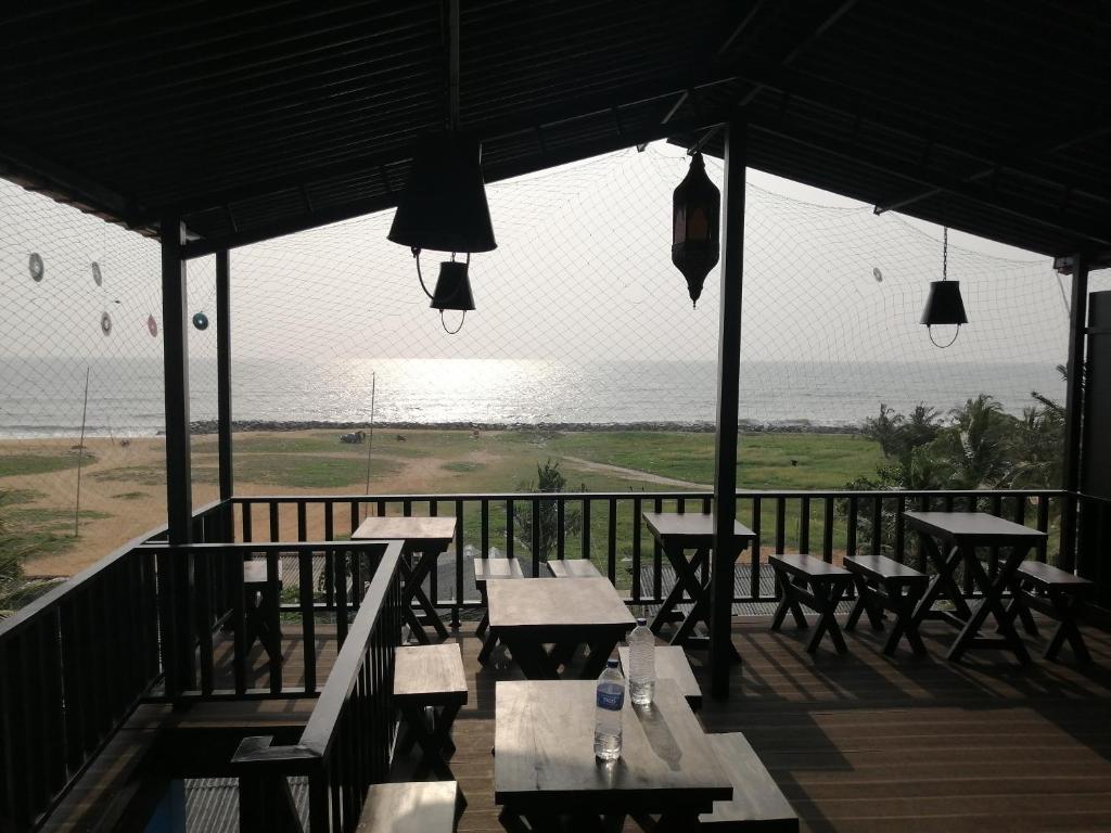 a porch with tables and chairs and a view of the ocean at Le Petit Hotel & Restaurant in Negombo