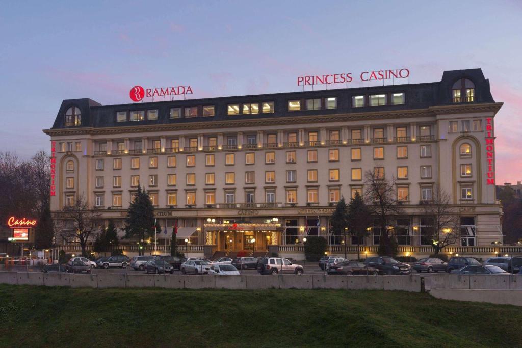 Ramada by Wyndham Plovdiv Trimontium في بلوفديف: مبنى كبير به سيارات تقف في موقف للسيارات