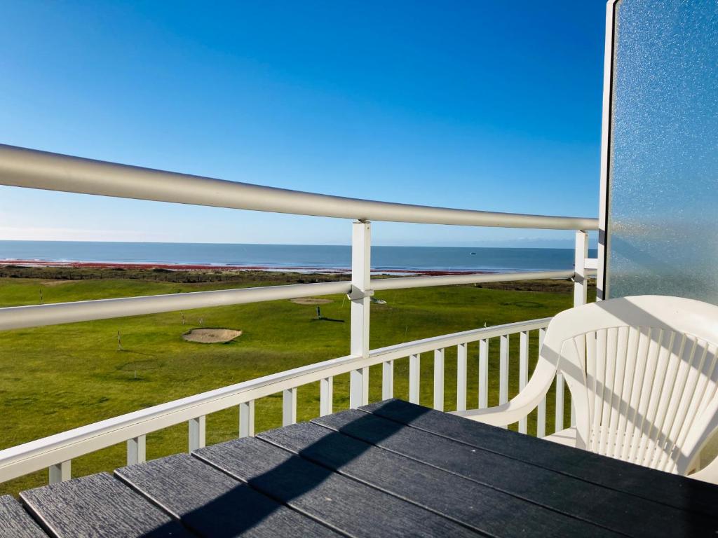 een balkon met een witte stoel en de oceaan bij Studio du golf, standing, piscine, forêt et océan in Saint-Jean-de-Monts