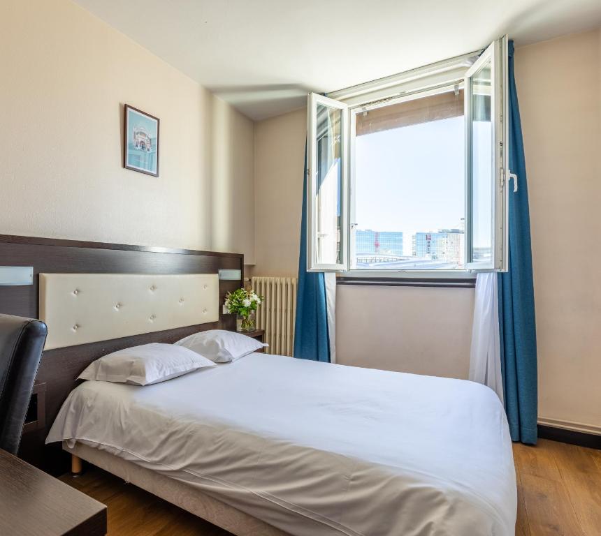 a bedroom with a large bed and a window at Hôtel Le Florin in Rennes