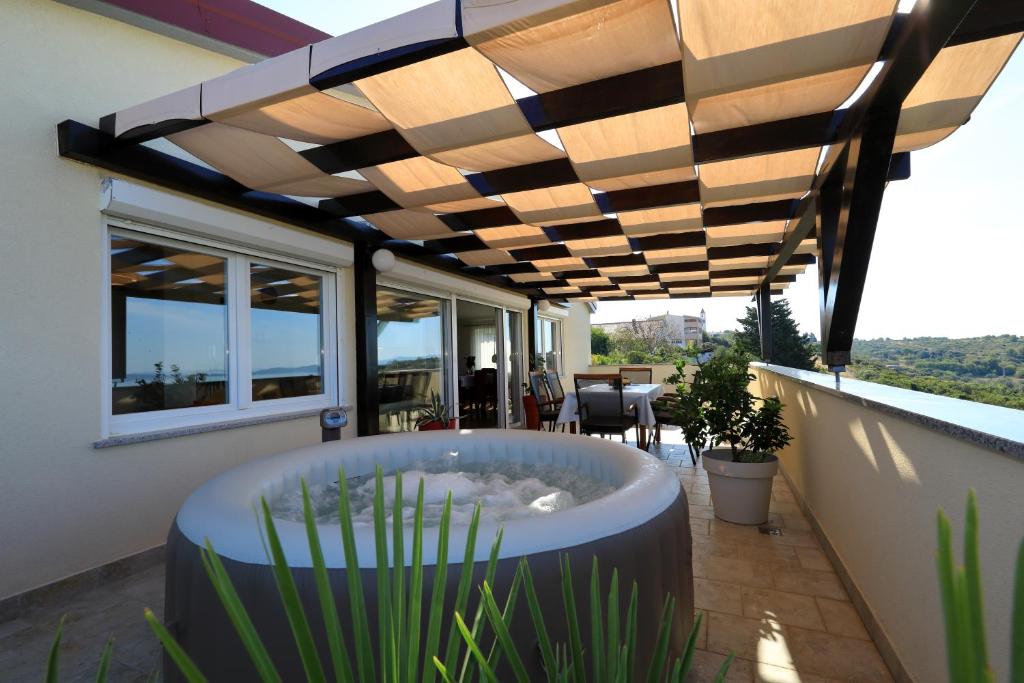 a patio with a hot tub under a wooden pergola at Vanda Land penthouse in Zadar