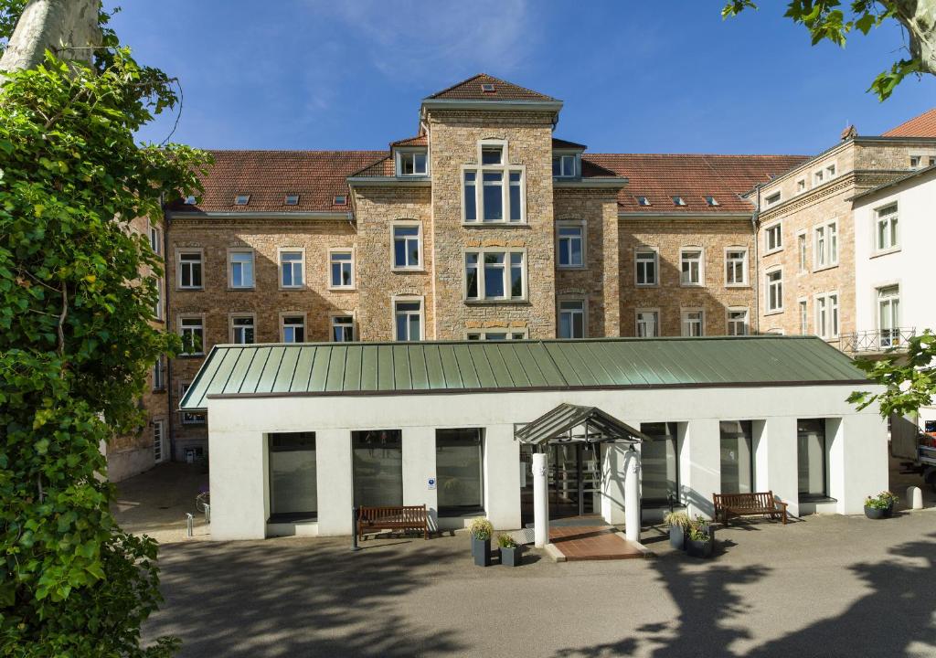 un grand bâtiment avec un garage blanc devant lui dans l'établissement Bildungshaus St. Bernhard - Wohnen und Tagen, à Rastatt