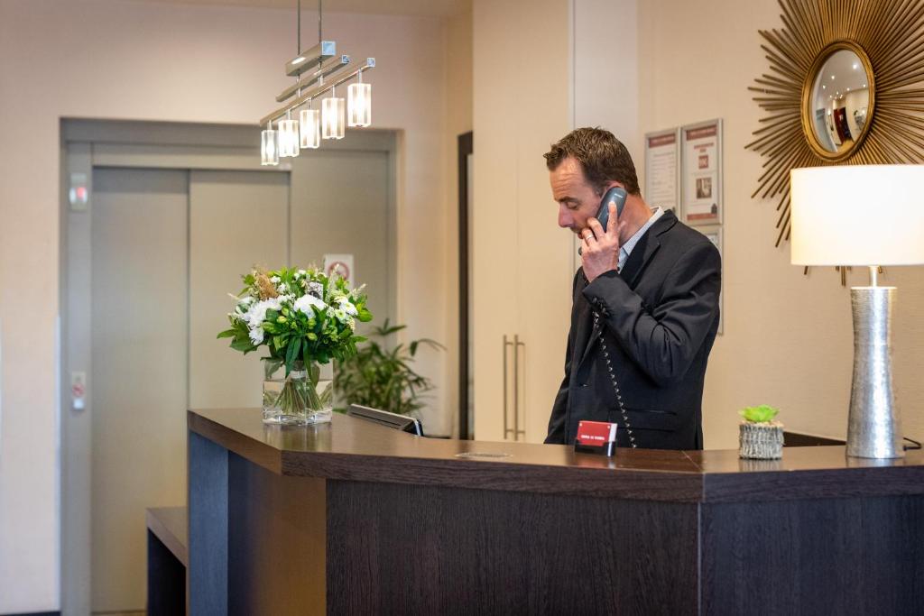 a man talking on a cell phone at a reception desk at Hôtel Le Florin in Rennes