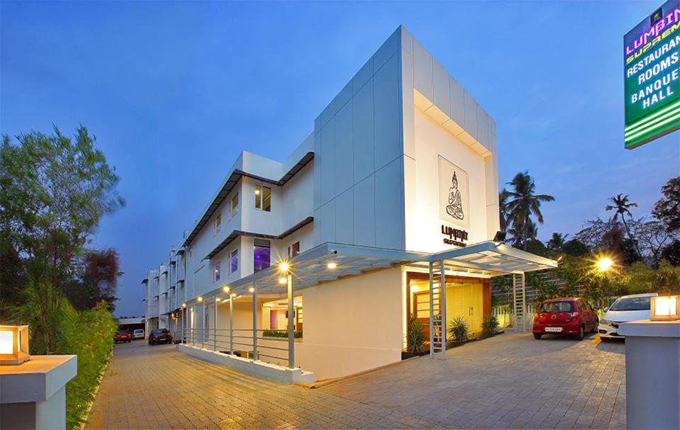 a large white building with a parking lot at night at Lumbini Supreme in Trichūr