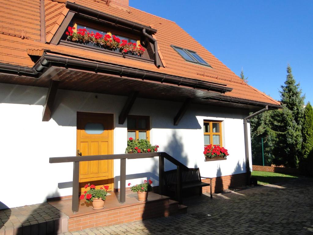 ein weißes Haus mit Blumenkästen und einer gelben Tür in der Unterkunft Giszowiec Pokoje gościnne Przyjazna 9 in Kattowitz