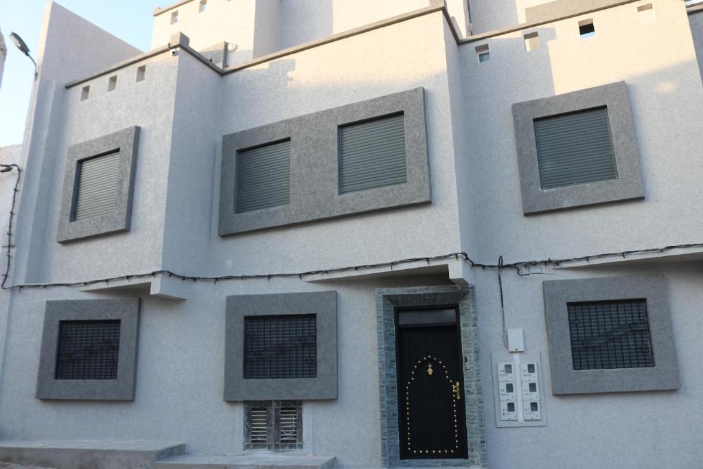 a building with a black door and windows at Tiwaline Tarsime App E in Sidi Ifni