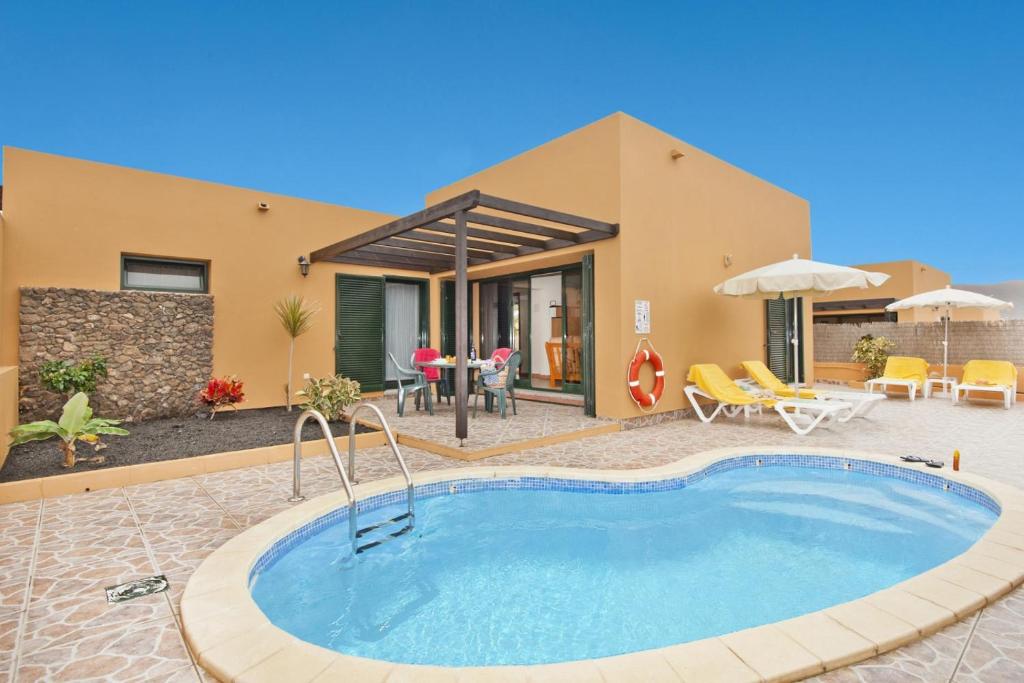 Villa con piscina frente a una casa en La Casa del Sol l by Best Holidays Fuerteventura, en Corralejo