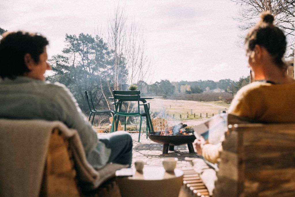 un groupe de personnes assises sur une terrasse avec foyer extérieur dans l'établissement de Wever Lodge, à Otterlo