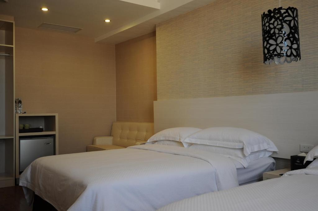 a bedroom with two beds with white sheets at The Riverside Hotel Hengchun in Hengchun South Gate
