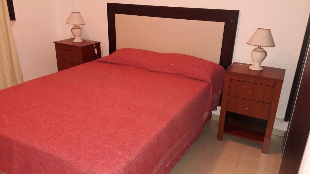 ヴィラ・カルロス・パスにあるDepartamento Sorrentosのベッドルーム1室(赤いベッド1台、ナイトスタンド2台付)